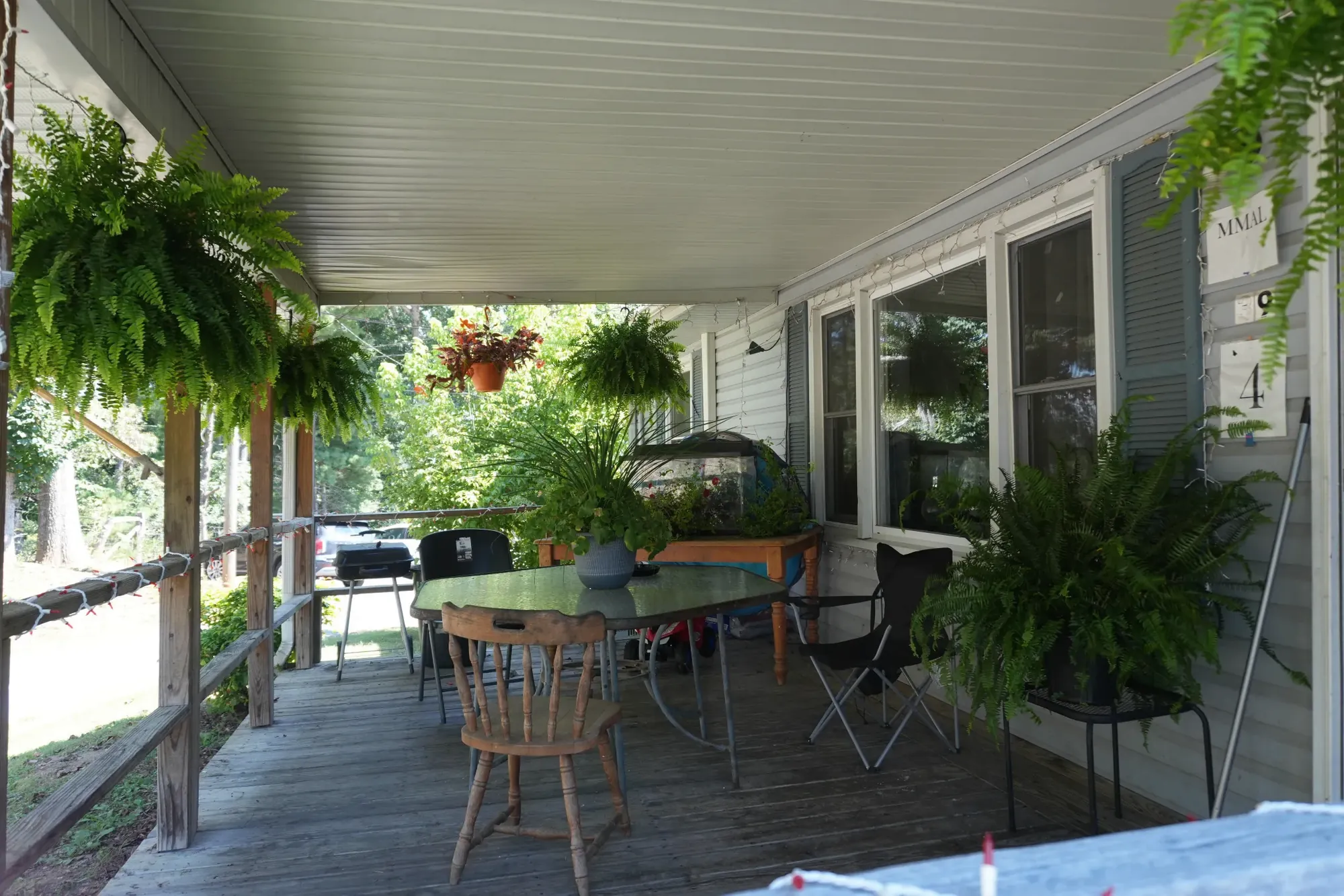 Chairs and a small table on the shaded porch, looking down its length.